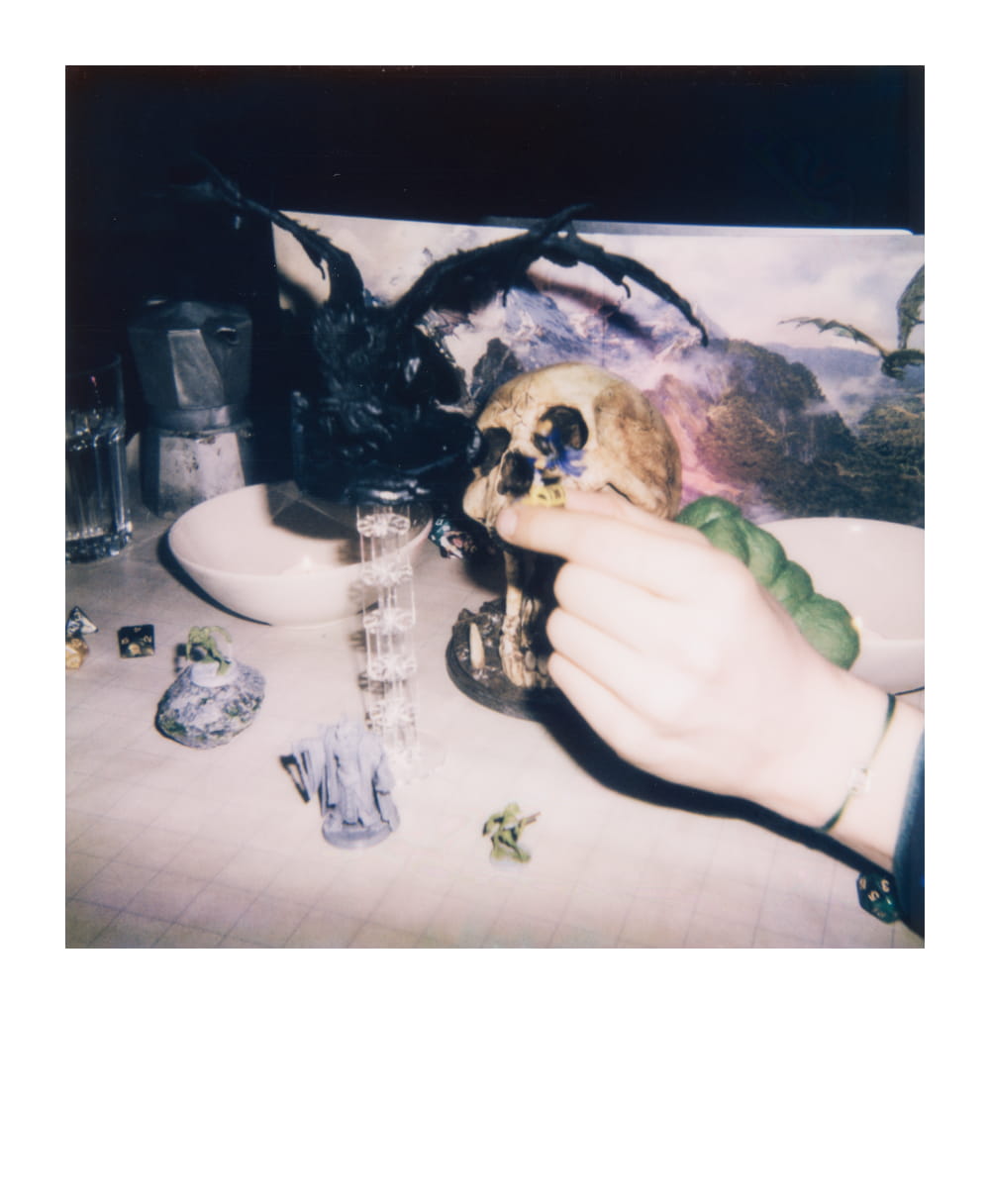 Close-up of a tabletop role-playing setup featuring a skull prop, dice, and miniatures, showcasing immersive gameplay.