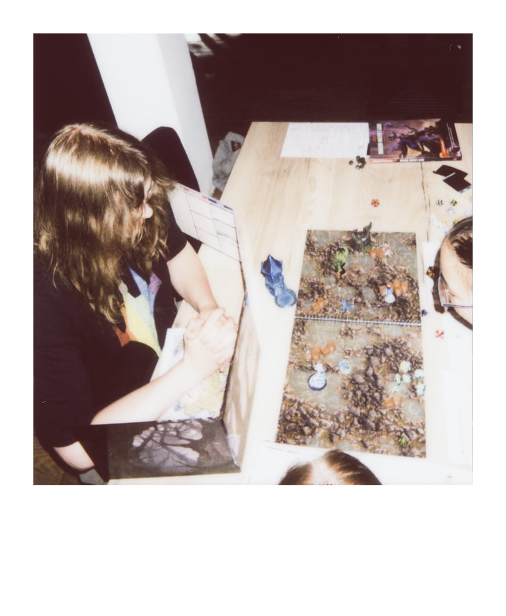 Player studies a detailed tabletop battle map covered with miniatures, dice and terrain pieces.